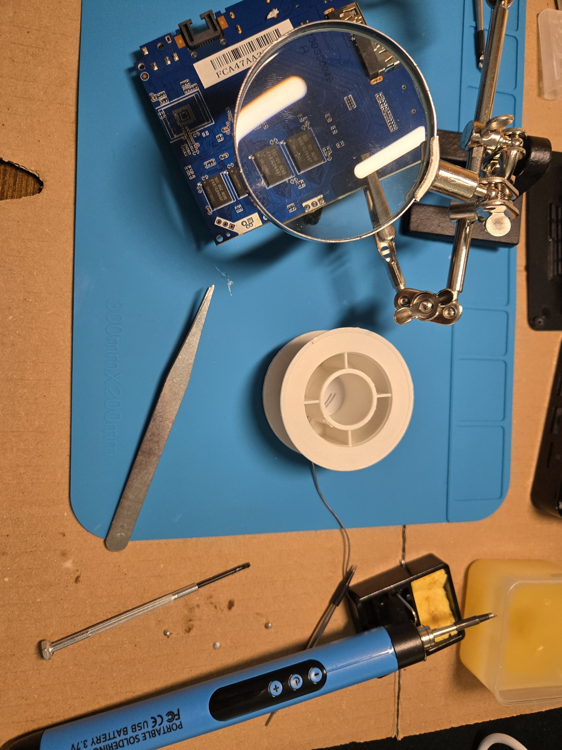 A soldering mat with electronics tools and a circuit board